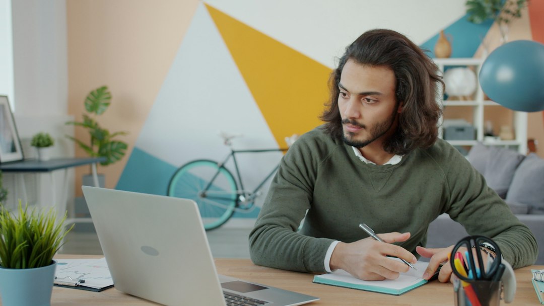 Researcher taking notes from a laptop at a desk